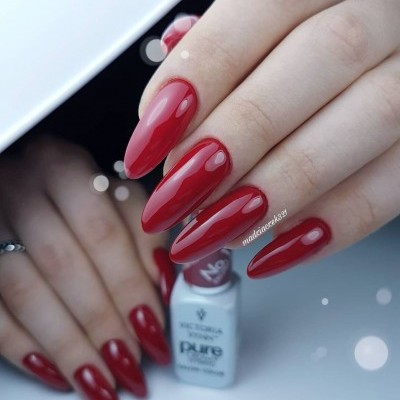 Unhas longas vermelhas brilhantes com frasco de verniz branco Victoria Vynn