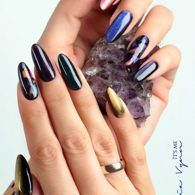 Unhas decoradas em vários tons metálicos segurando cristal de ametista