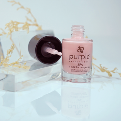 Frasco de verniz de unhas rosa claro com pincel ao lado sobre superfície branca com decoração seca