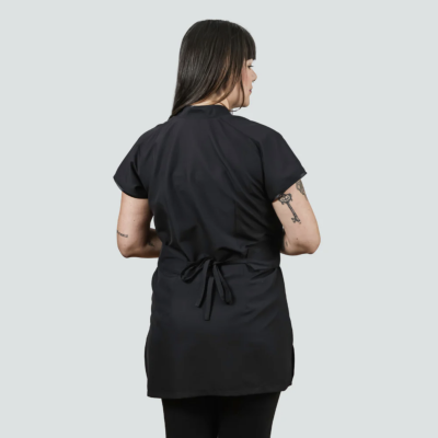 Mulher vista de costas a usar bata preta com laço amarrado e calças pretas