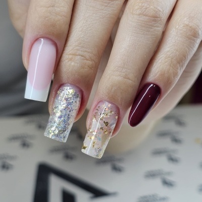 Mão com quatro unhas decoradas em diferentes estilos e cores