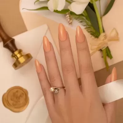 Mão feminina com anel de pérola e diamante e unhas pintadas em fundo com flores e carimbo de cera