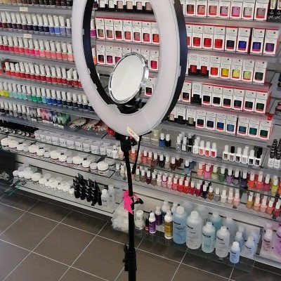 Ring light com suporte tripé preto e espelho circular numa loja de produtos de beleza