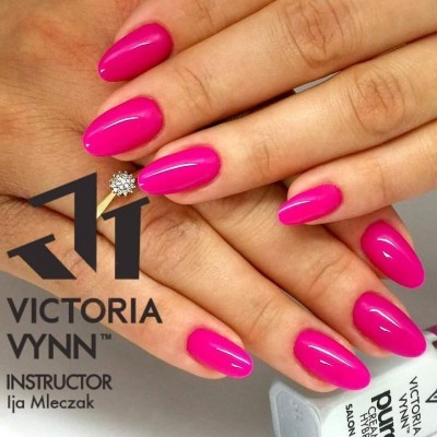 Unhas naturais pintadas de rosa vibrante brilhante segurando frasco de verniz VICTORIA VYNN
