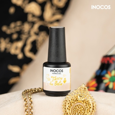 Garrafas de verniz gel Inocos com corrente dourada e pendente sobre superfície clara