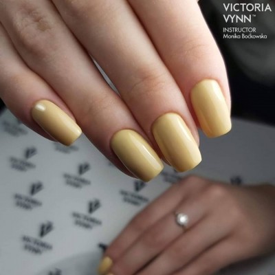 Unhas pintadas de amarelo pastel com fundo com logótipos VICTORIA VYNN