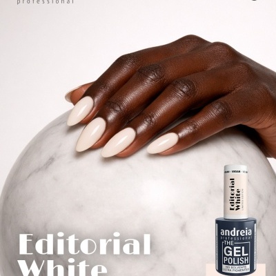 Mão com unhas brancas sobre esfera de mármore e frasco de verniz gel