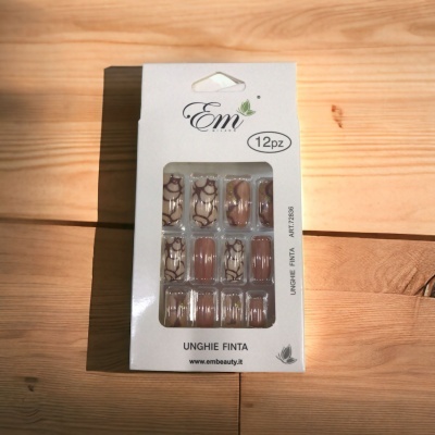 Caixa branca de unhas postiças decoradas em tons castanhos e bege com padrão, sobre madeira