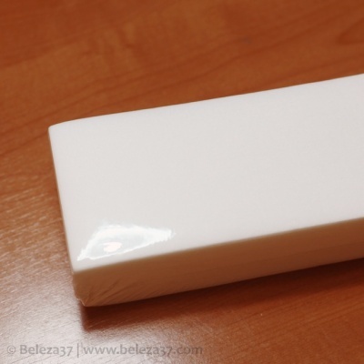 Bloco polidor de unhas branco rectangular sobre uma superfície de madeira castanha