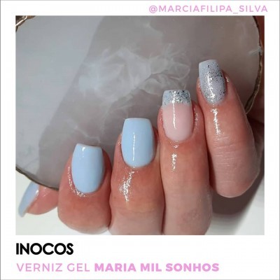 Unhas pintadas com verniz gel em azul claro, bege e glitter prateado nas pontas