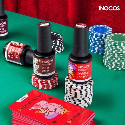 Frascos de verniz INOCOS sobre fichas de poker coloridas numa mesa verde.