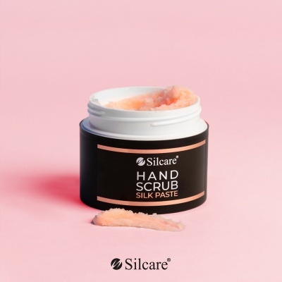 Frasco aberto de pasta esfoliante cor de pêssego Silcare Hand Scrub Silk Paste sobre fundo rosa