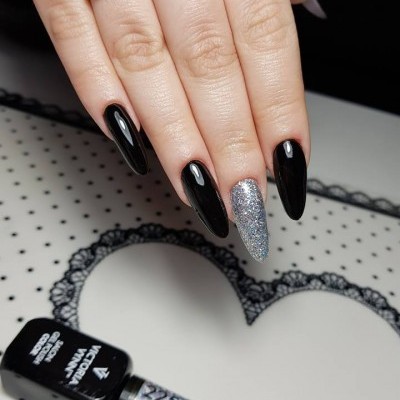 Unhas compridas em preto e glitter prateado com anel dourado e frasco de verniz gel