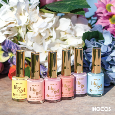 Vernizes de unhas pastel Inocos like gel com tampas douradas sobre superfície com flores coloridas ao fundo