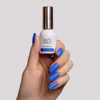 Frasco de verniz de unhas branco com tampa metálica prateada e texto, segurado por mão com unhas azuis