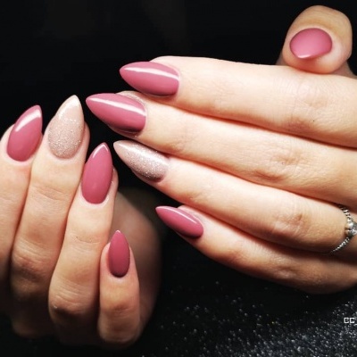 Mãos femininas com unhas em verniz rosa e glitter, anel prateado