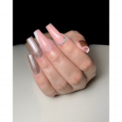 Unhas postiças compridas em tons nude e dourado com decoração de cristais.