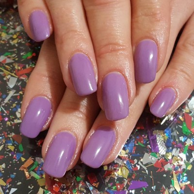 Mãos com unhas roxas brilhantes sobre glitter colorido