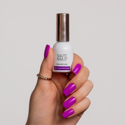 Mão segurando frasco de verniz de unhas branco com tampa metálica e texto da marca.