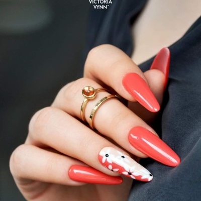 Unhas stiletto coral brilhantes com decoração branca e anéis dourados
