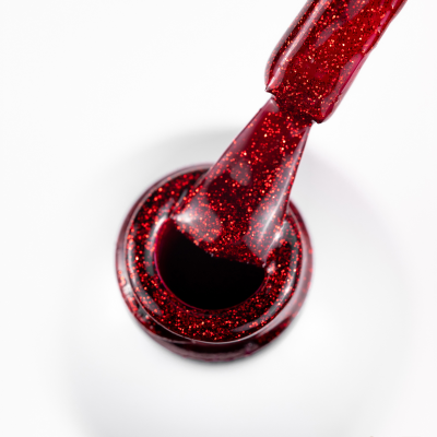 Frasco de verniz de unhas branco aberto com verniz vermelho com purpurinas e pincel aplicador