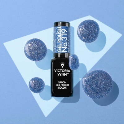 Frasco de verniz gel azul glitter Victoria Vynn sobre superfície azul com manchas do verniz