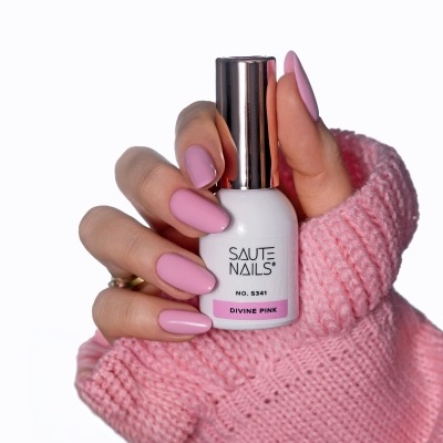 Frasco de verniz SAUTE NAILS com unhas pintadas de rosa e manga de malha rosa