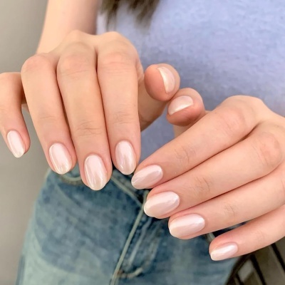 Mãos femininas com unhas pintadas de esmalte nude brilho