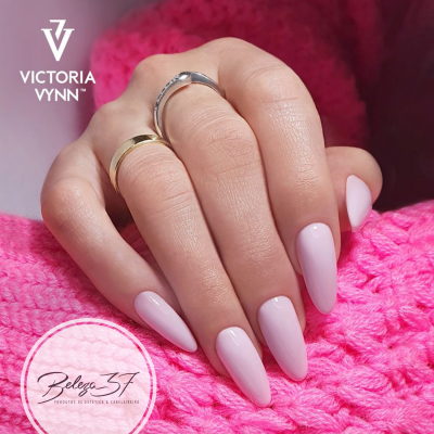 Mão com unhas rosa claro brilhante e argolas sobre tecido rosa tricotado