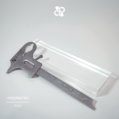 Paquímetro metálico cinzento com caixa transparente sobre superfície clara