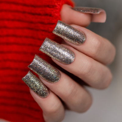 Unhas pintadas com verniz glitter prateado, suéter vermelho de malha ao fundo