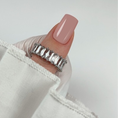 Anel prateado com pedras retangulares em mão com unha rosa fosco e manga branca