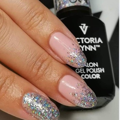 Unhas com verniz gel rosa claro e glitter prateado nas pontas, frasco de verniz gel preto ao fundo