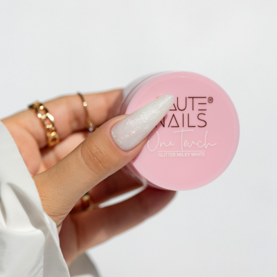 Frasco rosa de verniz para unhas com texto SAUTE NAILS, unhas compridas brancas peroladas.