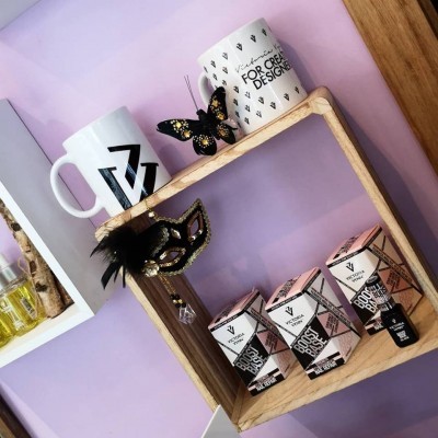 Canecas decorativas, máscara preta com penas, borboleta e frascos de perfume em prateleira de madeira