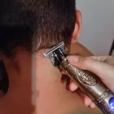 Máquina de cortar cabelo metálica bronze em uso na nuca