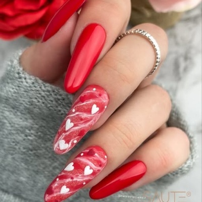 Unhas longas vermelhas com design de corações brancos e anel prateado