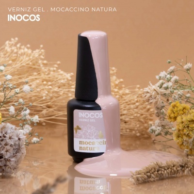 Frasco de verniz gel cor de rosa claro junto a flores secas