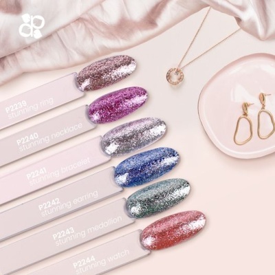 Vernizes glitter com código e nomes, colar com pendente circular e brincos dourados sobre pano rosa claro