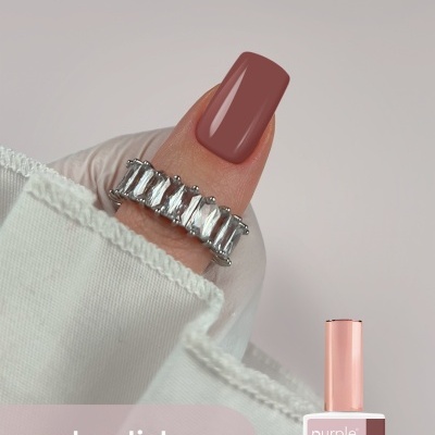 Esmalte gel Purple Professional cor 036 Shadow num dedo com anel prateado e fundo branco.