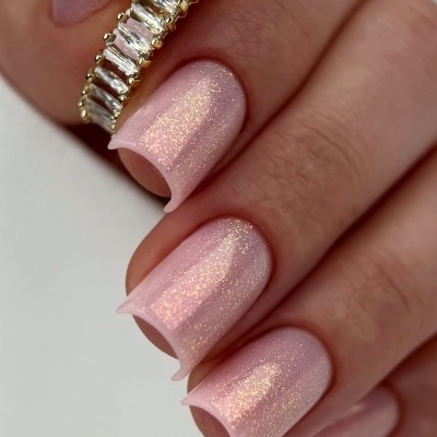 anel dourado com pedras retangulares e unhas rosa cintilantes
