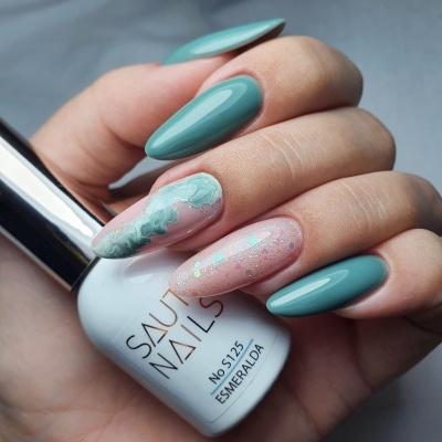 Unhas pintadas com verniz verde esmeralda e rosa com brilho, segurando frasco branco de verniz SAUR NAILS