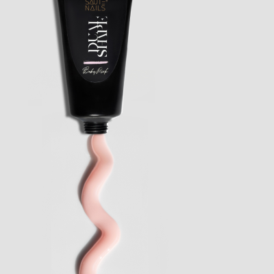 Tubo preto de esmalte cor-de-rosa espremido com texto SAUTE NAILS no tubo