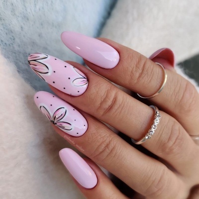 Unhas cor-de-rosa com flores desenhadas e anéis prateados