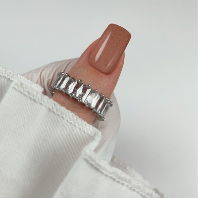 Anel com pedras transparentes no dedo polegar com unha castanha