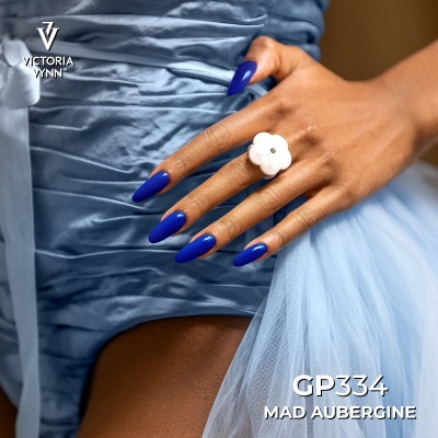 Mão com unhas azuis Mad Aubergine e anel branco sobre vestido azul acetinado e tule