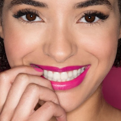 Rosto de mulher com batom rosa vibrante e fundo rosa.