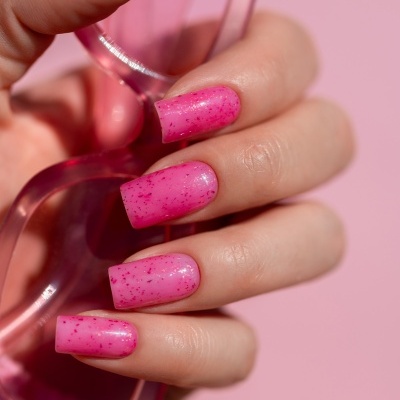 Mãos com unhas postiças rosa de glitter segurando objecto plástico transparente