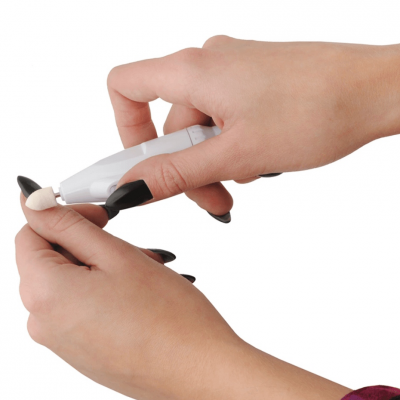 Dispositivo elétrico cinzento com ponta de esponja branca usado por mãos femininas com unhas pretas