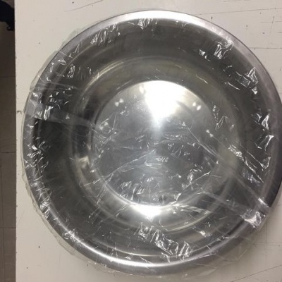 Tigela metálica redonda com plástico transparente sobre superfície branca